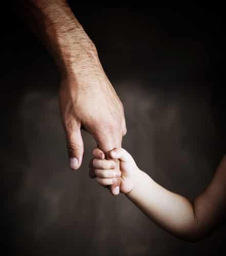 child reaching for man's hand