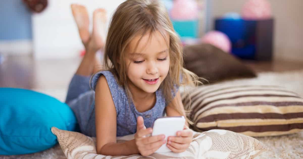 young girl looking at smartphone while on the bed